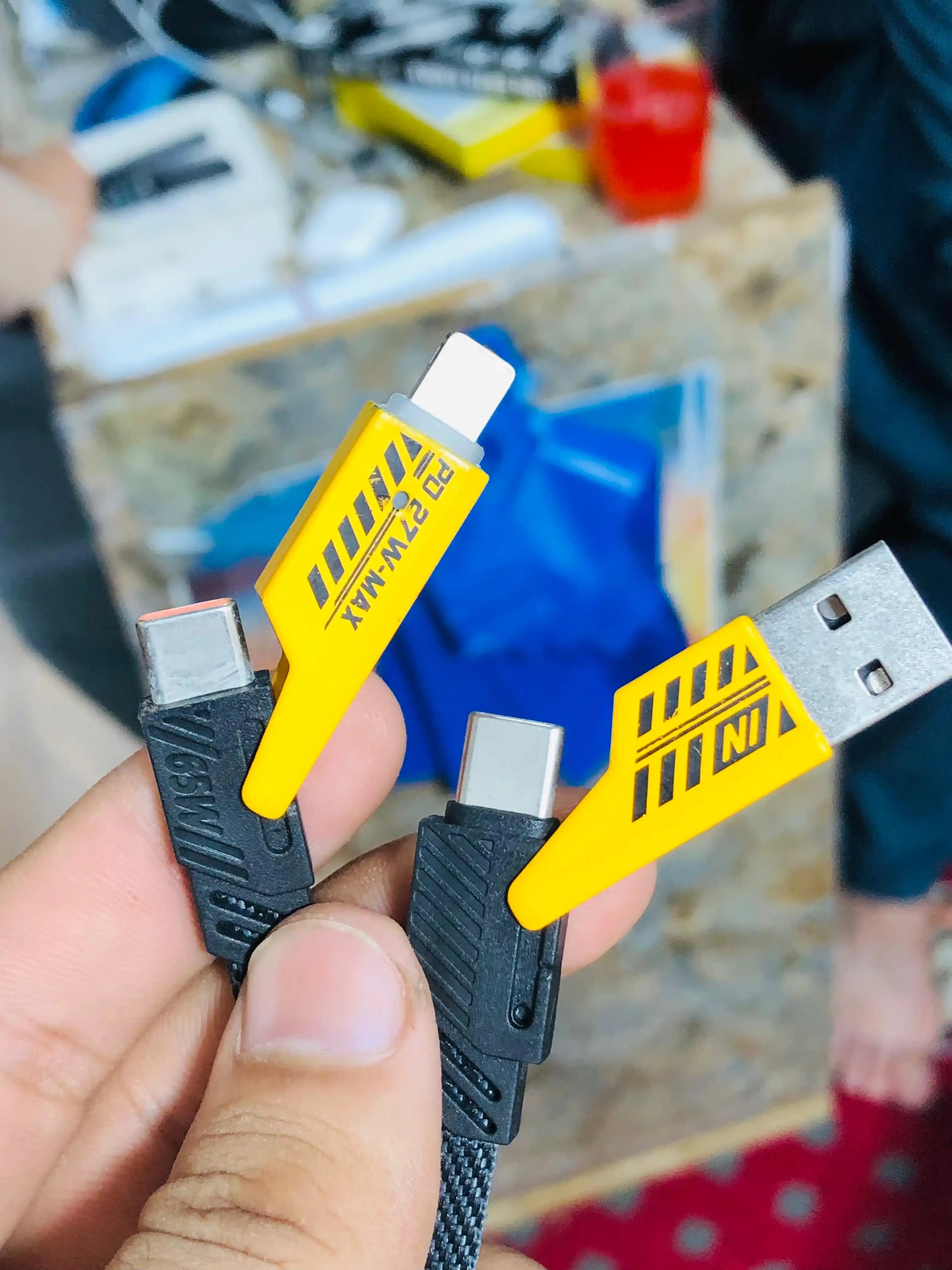 Two USB cables with yellow labels held by a hand, blurred background