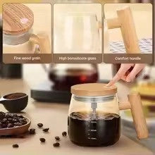 Glass coffee maker with wooden handle on a wooden surface with coffee beans and a cup.
