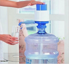 Person using a manual water pump to fill a glass with water from a large plastic container.