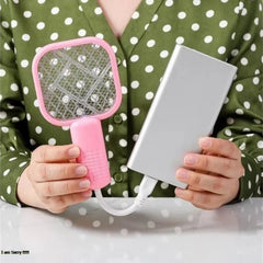 Person holding a pink fly swatter and a white power bank with a green polka dot shirt.